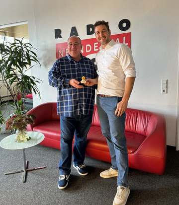 Radio Neandertal Moderator Daniela Patano und WILKA Geschäftsführer Robert Schlieper vor dem Radio Neandertal Logo